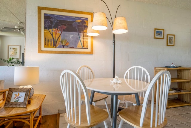 dining space with ceiling fan, tile patterned flooring, and a textured ceiling