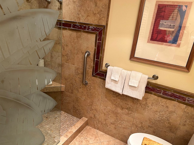 bathroom with tile patterned flooring, a tile shower, and toilet