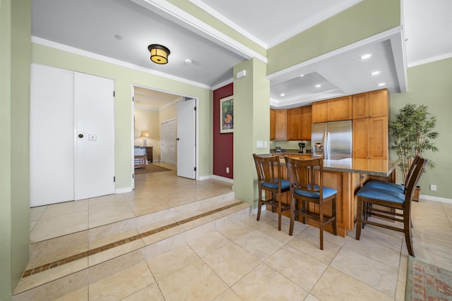 kitchen with a kitchen bar, kitchen peninsula, ornamental molding, light tile patterned floors, and stainless steel fridge with ice dispenser