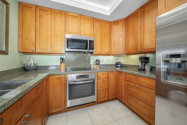 kitchen with stone counters, light tile patterned floors, and stainless steel appliances