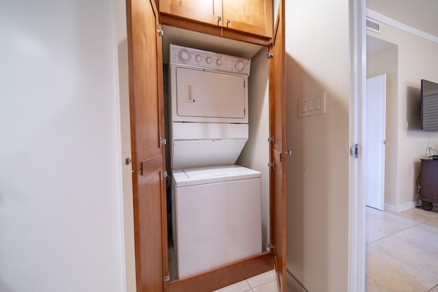 laundry room with light tile patterned flooring and stacked washer and clothes dryer