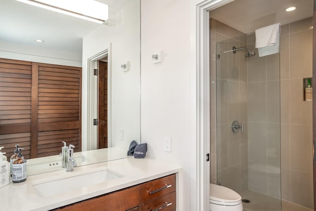 bathroom featuring vanity, a shower with shower door, and toilet