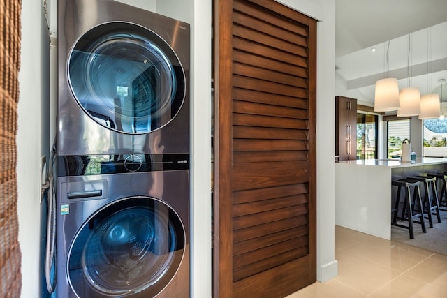 laundry area featuring light tile patterned floors and stacked washer and clothes dryer