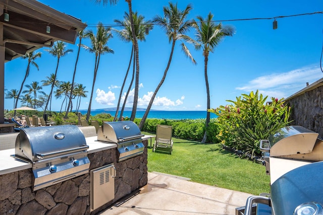 view of patio featuring an outdoor kitchen, a water view, and grilling area