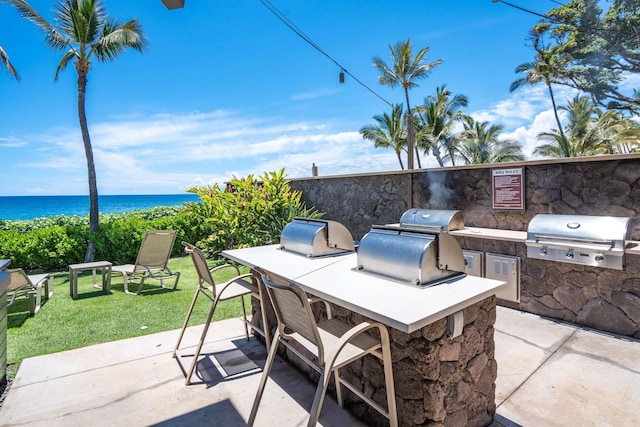 view of patio with an outdoor kitchen, a water view, and grilling area