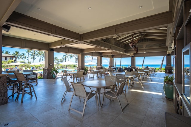 sunroom / solarium featuring a water view and lofted ceiling with beams