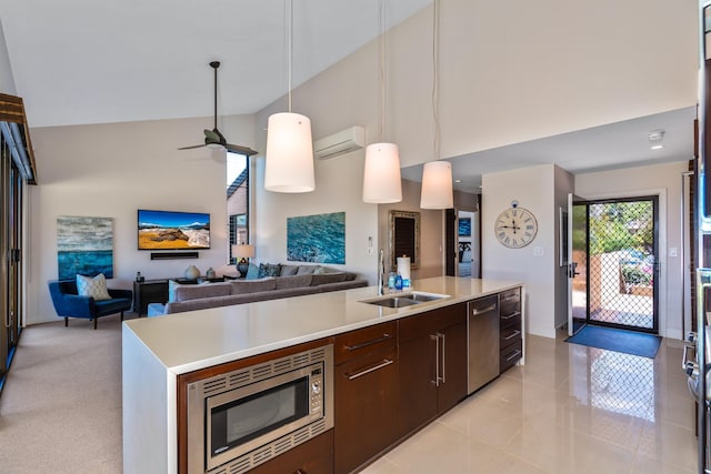 kitchen with sink, an AC wall unit, decorative light fixtures, a kitchen island with sink, and appliances with stainless steel finishes