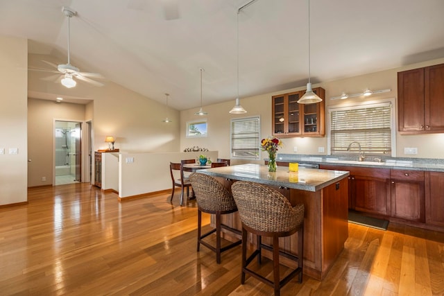 kitchen featuring a center island, stone counters, sink, ceiling fan, and wood-type flooring