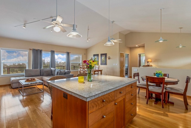 kitchen featuring lofted ceiling, ceiling fan, light wood-type flooring, decorative light fixtures, and a kitchen island