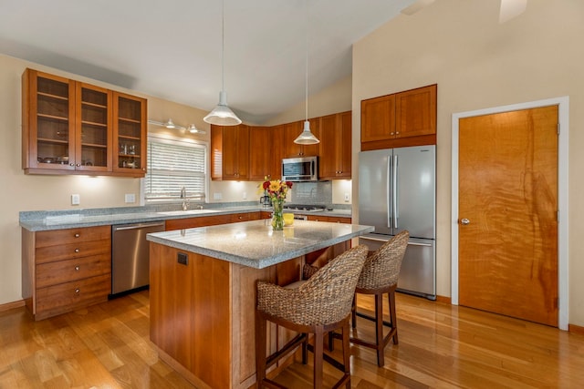 kitchen with pendant lighting, a center island, sink, appliances with stainless steel finishes, and light stone counters