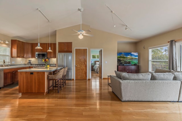 50 Uakoko Pl, Haiku, HI 96708 - kitchen with stainless steel appliances, rail lighting, brown cabinetry, open floor plan, and high vaulted ceiling