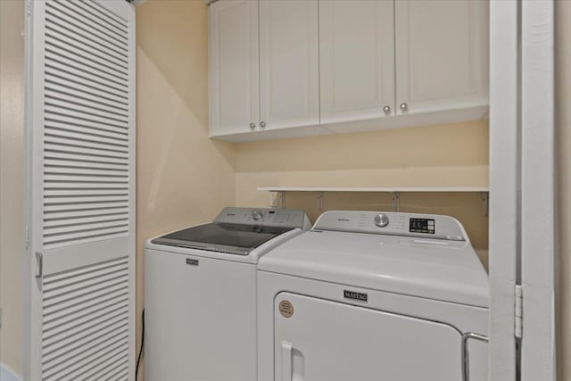 clothes washing area with cabinets and independent washer and dryer