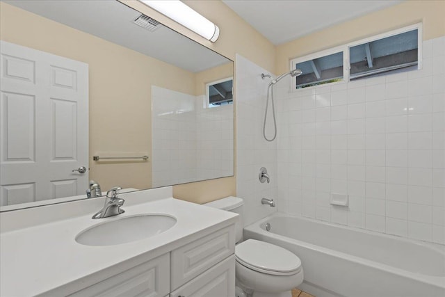 full bathroom with vanity, tiled shower / bath combo, and toilet