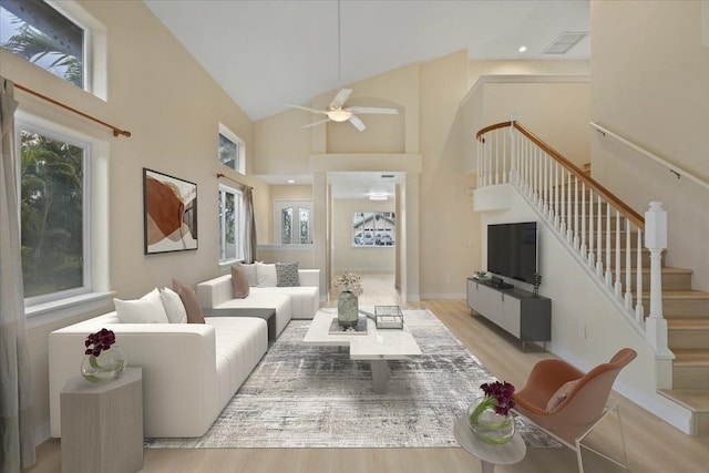 living room with light hardwood / wood-style floors, high vaulted ceiling, and ceiling fan