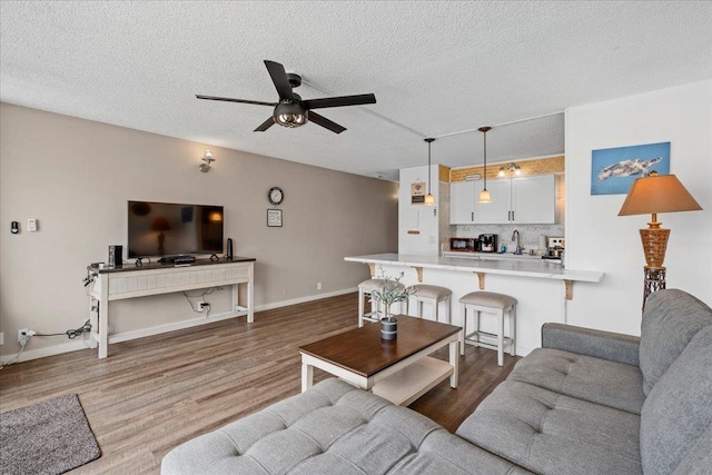 1993 S Kihei Rd Unit 308, Kihei, HI 96753 - living room with ceiling fan, wood finished floors, a textured ceiling, bar with sink, and baseboards