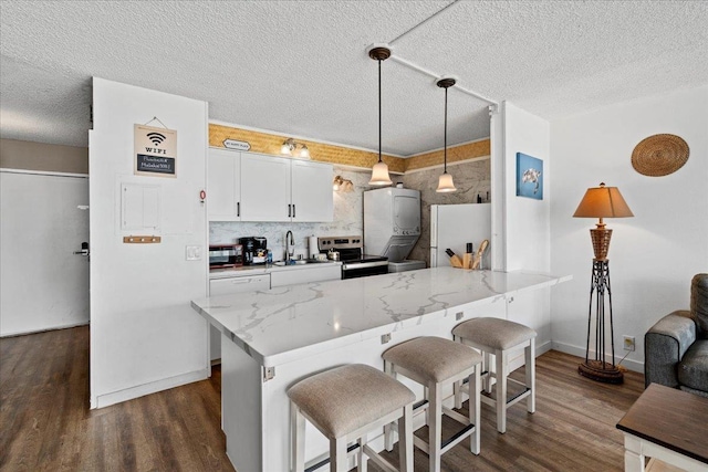 1993 S Kihei Rd Unit 308, Kihei, HI 96753 - kitchen with freestanding refrigerator, a breakfast bar, dark wood-style flooring, stainless steel range with electric stovetop, and a textured ceiling
