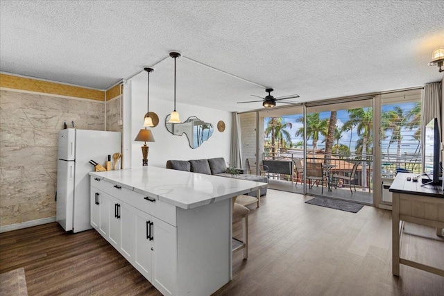 1993 S Kihei Rd Unit 308, Kihei, HI 96753 - kitchen with freestanding refrigerator, dark wood finished floors, a peninsula, white cabinets, and open floor plan