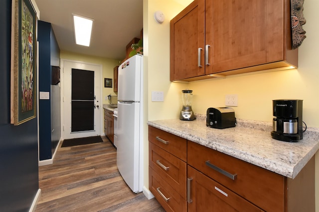 kitchen featuring light stone countertops, dark hardwood / wood-style flooring, and white fridge