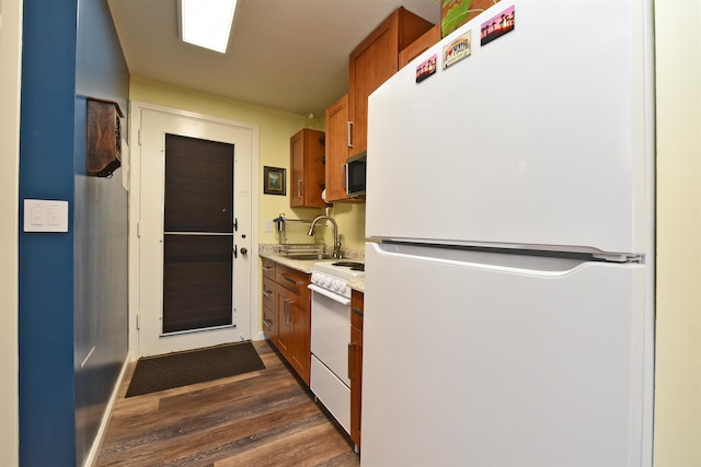 kitchen featuring sink, dark wood-type flooring, and white appliances