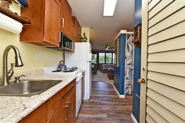 kitchen with white range, sink, ceiling fan, light stone countertops, and dark hardwood / wood-style flooring