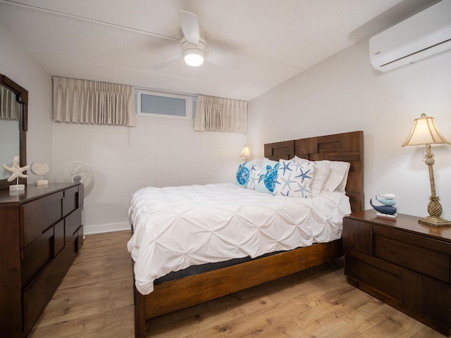 bedroom featuring ceiling fan, light hardwood / wood-style floors, and a wall mounted air conditioner