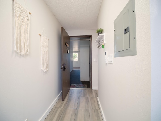 hall featuring a textured ceiling, electric panel, and light hardwood / wood-style floors