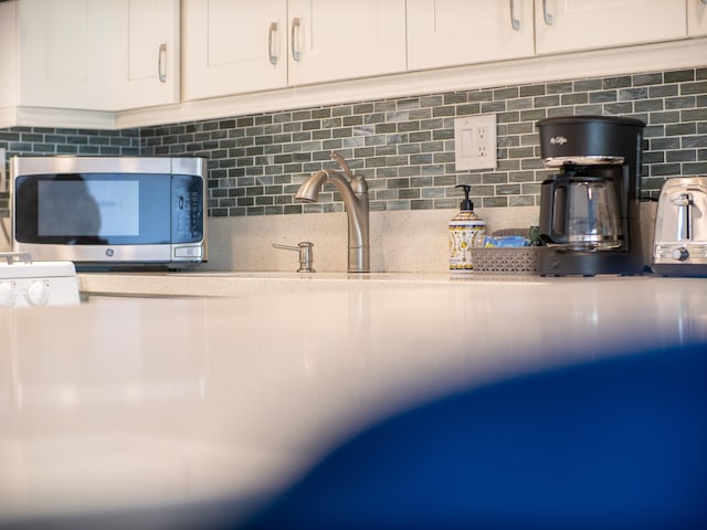 details featuring decorative backsplash and white cabinetry