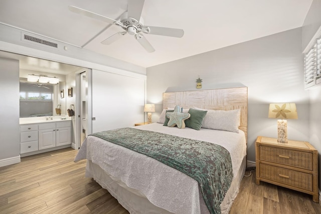 bedroom featuring ceiling fan, light hardwood / wood-style flooring, and ensuite bath