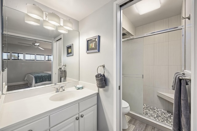 bathroom featuring hardwood / wood-style flooring, toilet, vanity, and a shower with door