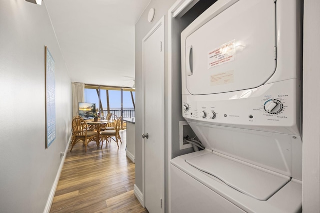 laundry room featuring stacked washer and clothes dryer and hardwood / wood-style floors