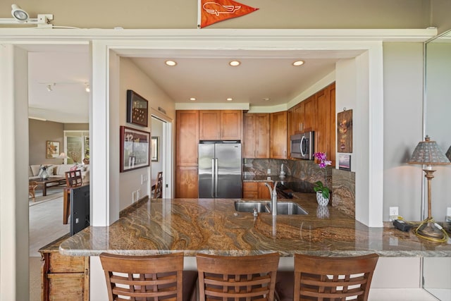 kitchen with a kitchen bar, kitchen peninsula, appliances with stainless steel finishes, and sink