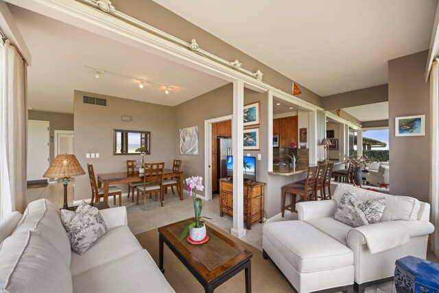 tiled living room with a healthy amount of sunlight and rail lighting