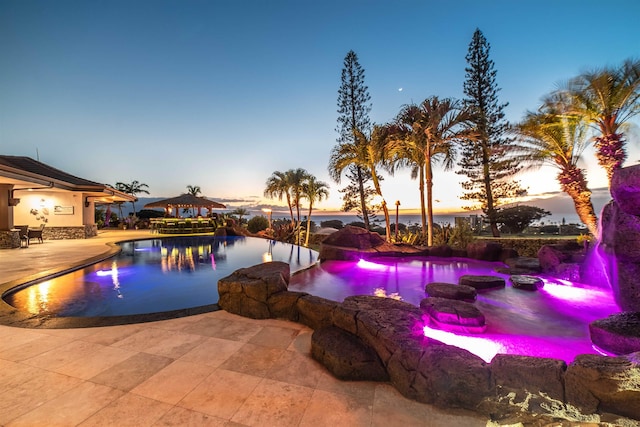 pool at dusk featuring a patio