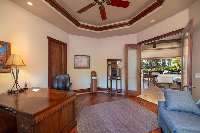 office featuring a tray ceiling, ceiling fan, ornamental molding, and dark hardwood / wood-style floors