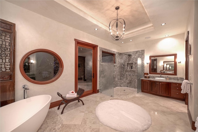 bathroom featuring a chandelier, vanity, a raised ceiling, and independent shower and bath