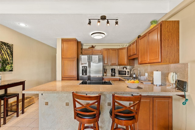 kitchen featuring a kitchen bar, kitchen peninsula, light tile patterned floors, and stainless steel appliances