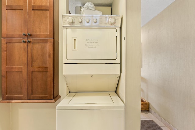 laundry room with tile patterned flooring and stacked washing maching and dryer