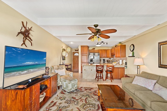 living room featuring beamed ceiling, light hardwood / wood-style flooring, and ceiling fan