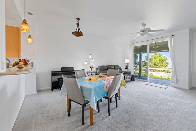 dining space with ceiling fan and light colored carpet