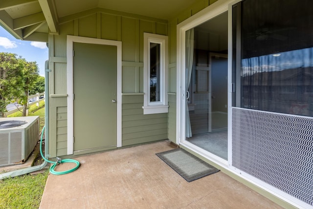 view of exterior entry featuring a patio and central AC unit