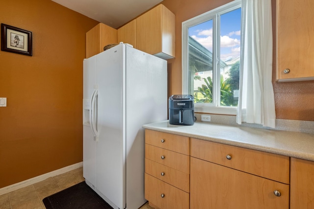 kitchen with a healthy amount of sunlight, light tile patterned flooring, white refrigerator with ice dispenser, and light brown cabinets