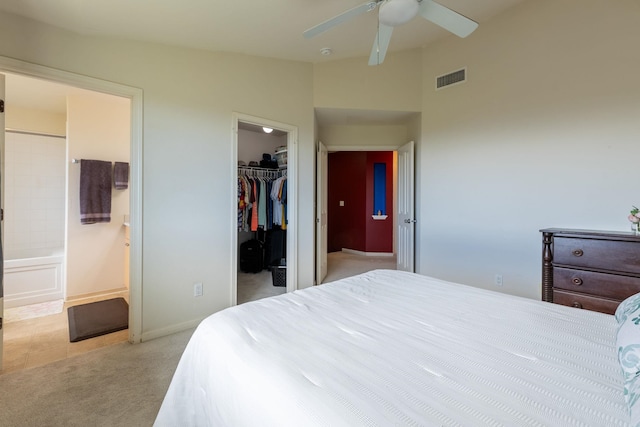 bedroom featuring connected bathroom, ceiling fan, a spacious closet, lofted ceiling, and light carpet