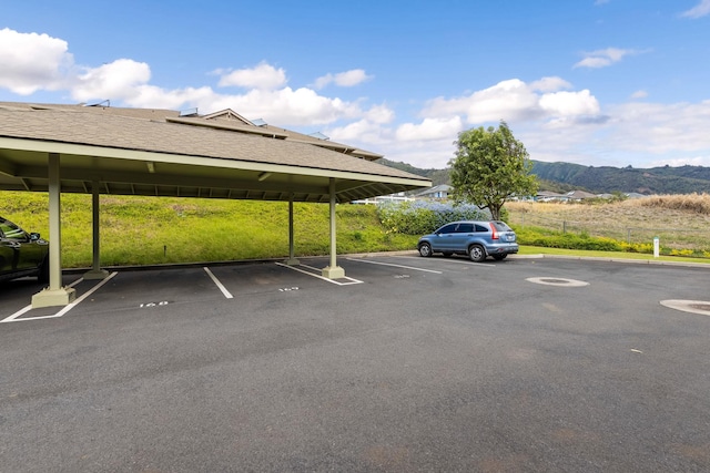 view of vehicle parking with a mountain view and a carport