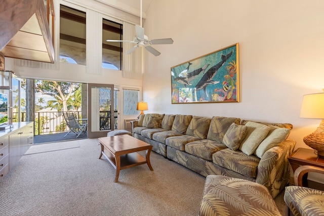 living room featuring carpet, ceiling fan, and a towering ceiling