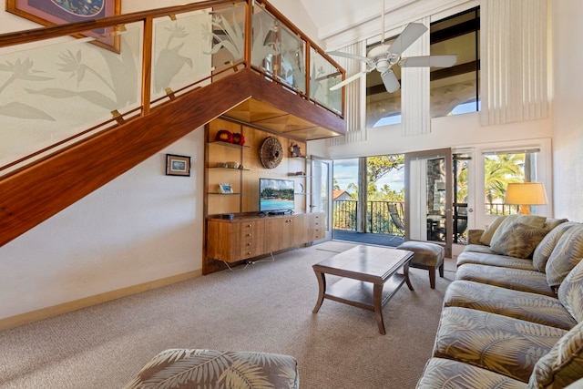 carpeted living room featuring a towering ceiling and ceiling fan