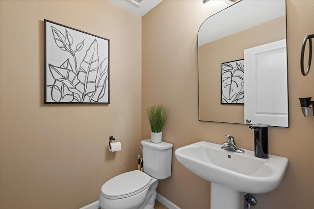 bathroom featuring a sink, baseboards, and toilet