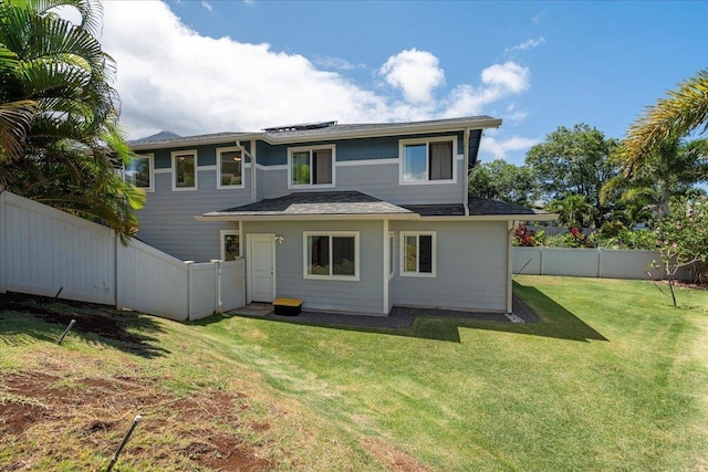 rear view of house with a fenced backyard and a yard