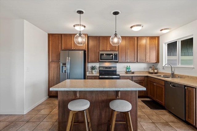 kitchen featuring a breakfast bar area, appliances with stainless steel finishes, a sink, and tile patterned flooring