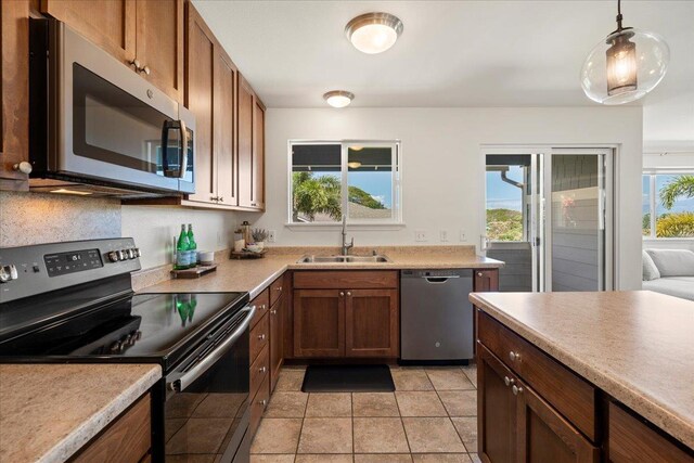 kitchen with a sink, appliances with stainless steel finishes, brown cabinets, and light countertops