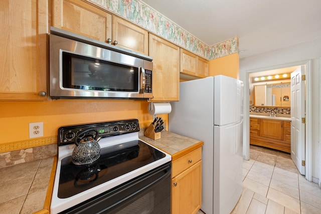 kitchen with backsplash, white appliances, light brown cabinetry, tile counters, and light tile patterned floors